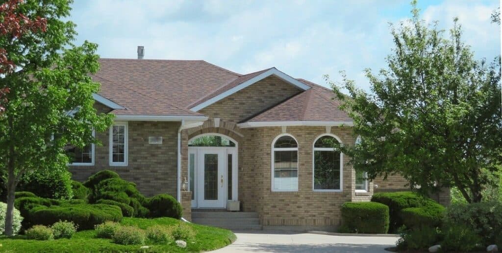 a suburban brick home with a brown roof